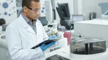 Medical research. Professional chemist young African man writing on his clipboard while working at the laboratory ethnicity profession occupation people medicine clinical biology internship copyspace