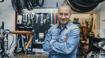 Stylish bicycle mechanic standing in his workshop. The best bicycle repair man in town. Bicycle Mechanic. A man working in a bicycle repair shop (Stylish bicycle mechanic standing in his workshop. The best bicycle repair man in town. Bicycle Mechanic.