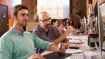 Designers Working Together At Desks In Modern Office