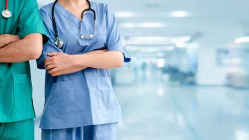 2 nurses standing in a hospital hallway with their arms crossed