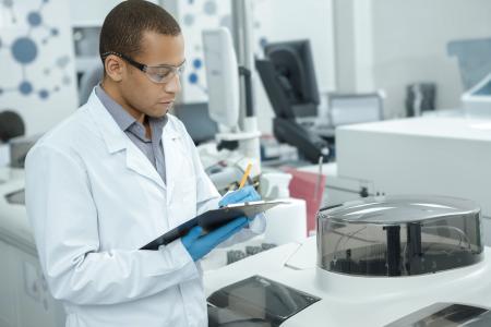 Medical research. Professional chemist young African man writing on his clipboard while working at the laboratory ethnicity profession occupation people medicine clinical biology internship copyspace
