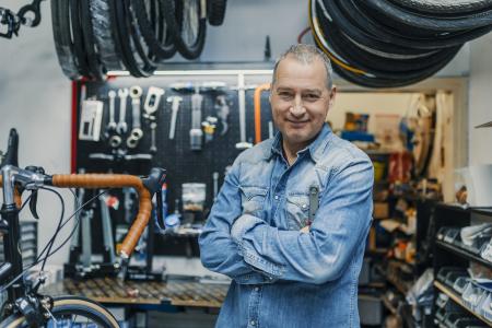 Stylish bicycle mechanic standing in his workshop. The best bicycle repair man in town. Bicycle Mechanic. A man working in a bicycle repair shop (Stylish bicycle mechanic standing in his workshop. The best bicycle repair man in town. Bicycle Mechanic.