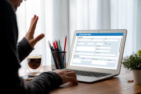 Person submitting an application form on a laptop